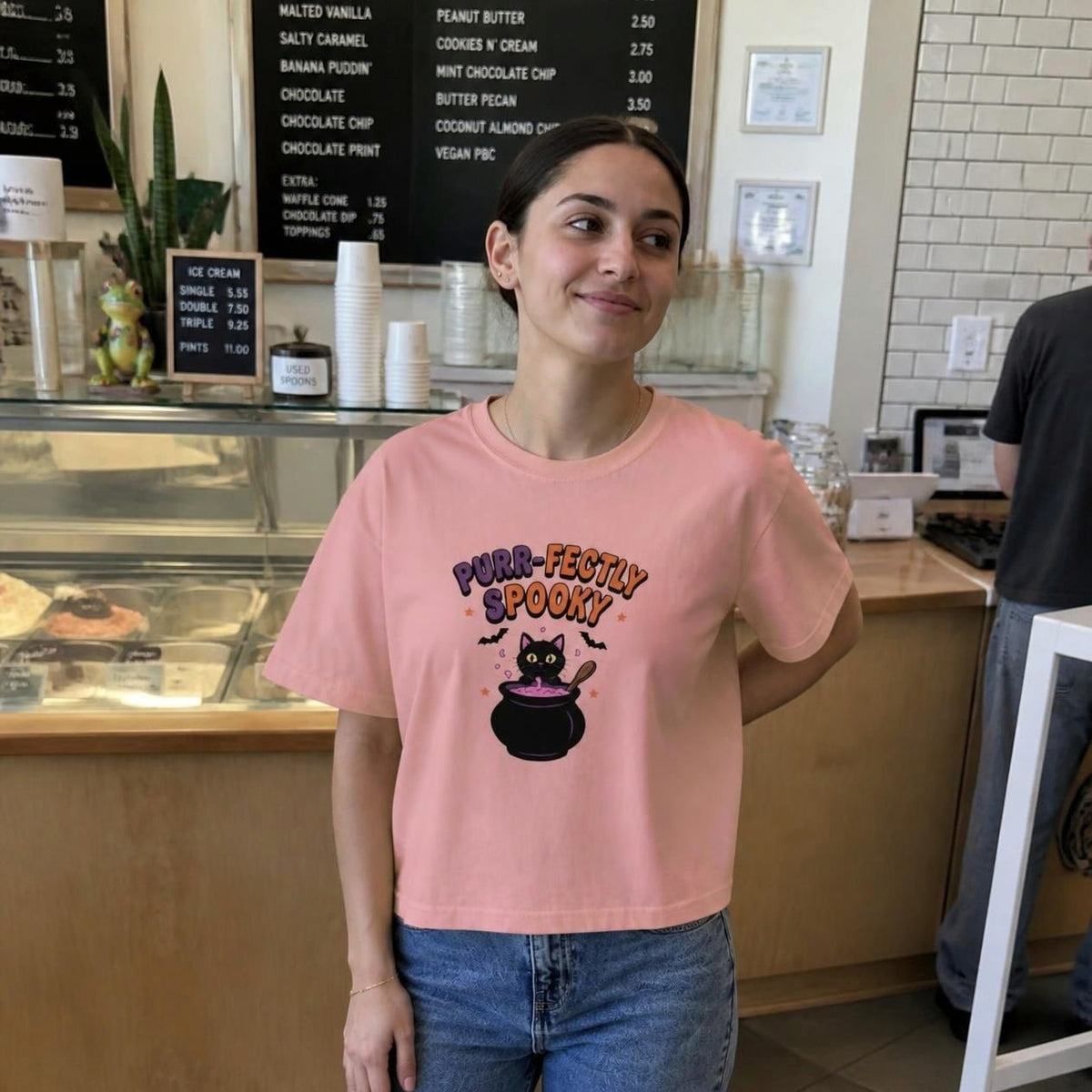 Woman wearing the peachy Purr-fectly Spooky Black Cat boxy crop tee, lifestyle photo (Color: Peachy)